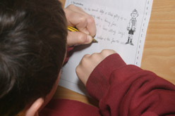 A left-handed child writing a paragraph of text.