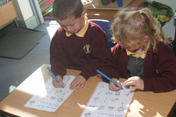 Children working together to complete a task using a pencil.