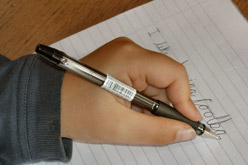 A left-handed person writing in joined up writing.