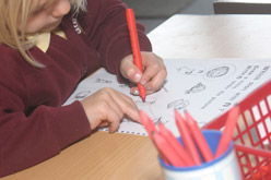 A child using a pencil at school.