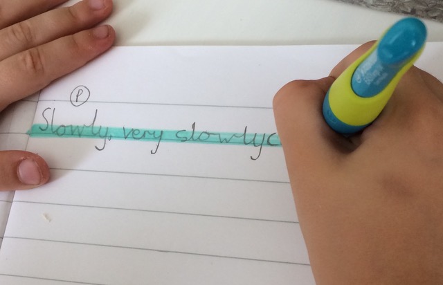 A child uses a highlighter pen to highlight their handwriting