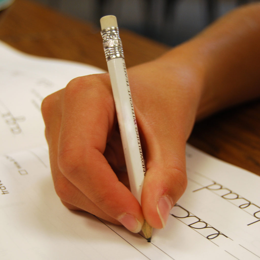 Child writing with a pencil, showing a good grip